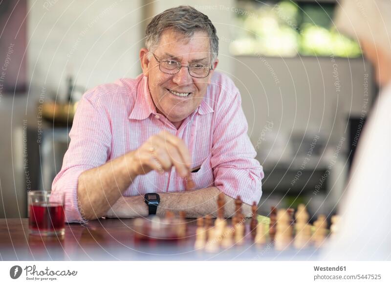 Älteres Ehepaar spielt zu Hause Schach lächeln spielen Paar Pärchen Paare Partnerschaft Zuhause daheim Senior ältere Männer älterer Mann Senioren Brettspiel