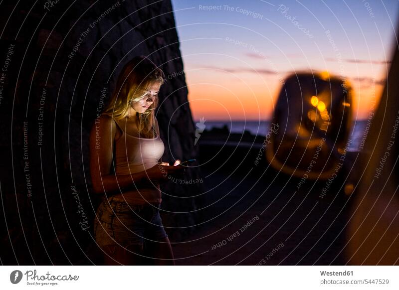 Frau benutzt Handy bei Sonnenuntergang benutzen benützen Smartphone iPhone Smartphones weiblich Frauen Meer Meere Campingbus Sonnenuntergänge Mobiltelefon