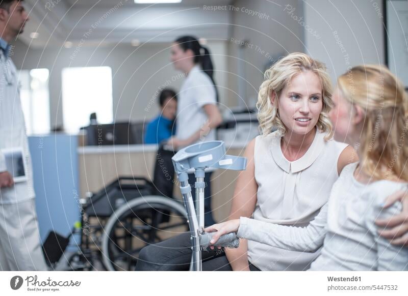 Mädchen mit Krücken sitzt mit ihrer Mutter im Empfangsbereich warten Besuch besuchen besorgt Sorgen Patientin Kranke Patientinnen Rollstuhl Rollstühle