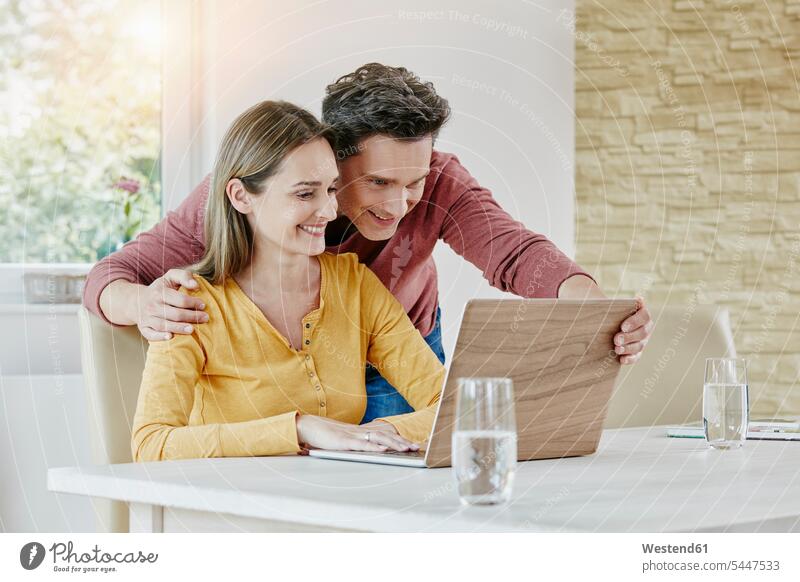Glückliches Paar zu Hause mit Laptop Notebook Laptops Notebooks lächeln Pärchen Paare Partnerschaft ansehen glücklich glücklich sein glücklichsein Internet