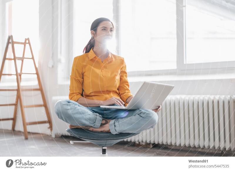 Junge Frau sitzt in ihrer neuen Wohnung mit einem Laptop weiblich Frauen jung Leiter Leitern Umzug umziehen Notebook Laptops Notebooks Erwachsener erwachsen