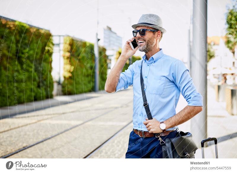 Reisende in der Stadt am Telefon telefonieren anrufen Anruf telephonieren lächeln Handy Mobiltelefon Handies Handys Mobiltelefone Mann Männer männlich