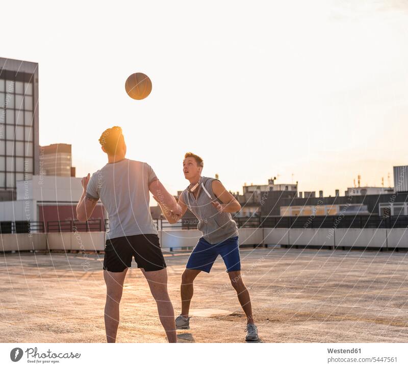 Freunde spielen bei Sonnenuntergang auf einem Dach Basketball Spaß Spass Späße spassig Spässe spaßig jung Basketbaelle Basketbälle fit Herausforderung