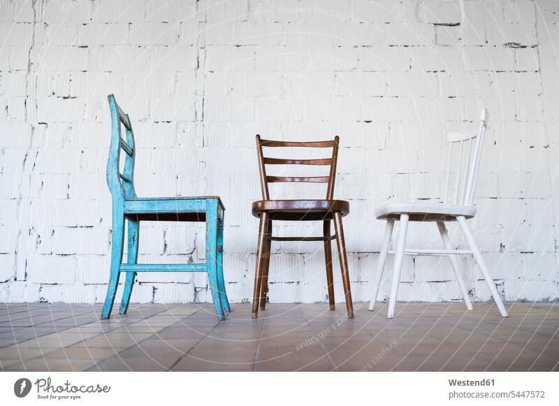 Leere Stühle gegen weiße Ziegelmauer Stuhl Stuehle unterschiedlich Backsteinwand Backsteinmauern verschieden verschiedene Variation Abweichung Variationen