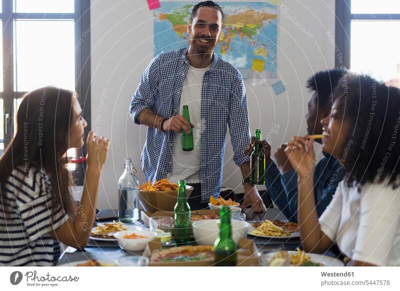 Eine Gruppe von Freunden, die sich zu Hause bei Bier und Fastfood treffen Tisch Tische Pizza Pizzen essen essend trinken Alkohol Alkoholische Getraenke