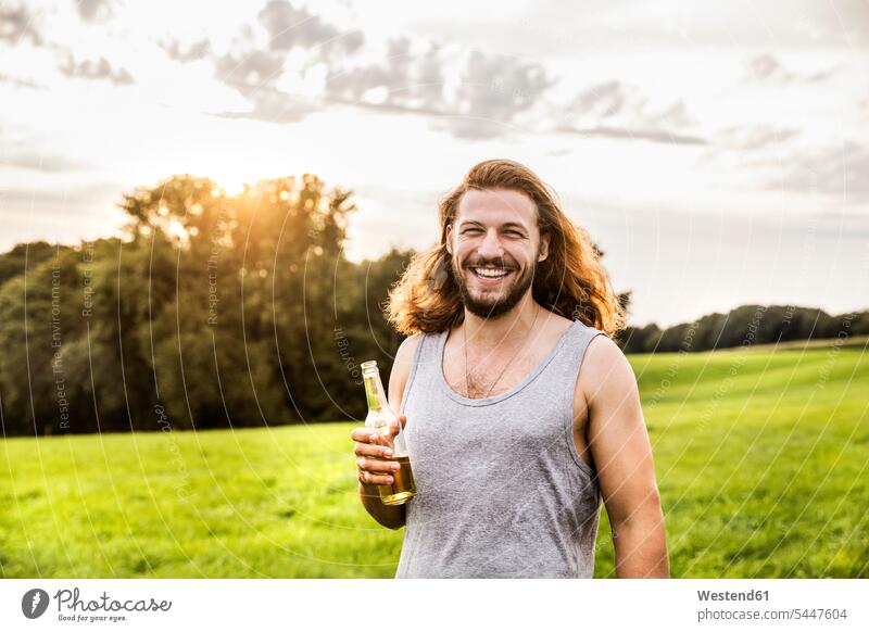 Porträt eines glücklichen Mannes, der Bier in einer ländlichen Landschaft trinkt Spaß Spass Späße spassig Spässe spaßig trinken lachen Portrait Porträts
