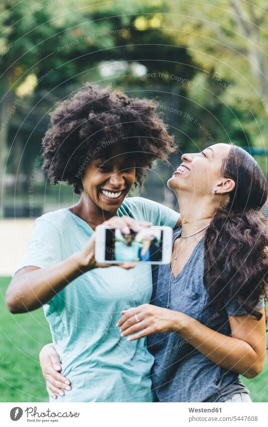 Zwei glückliche beste Freunde nehmen Selfie mit Smartphone in einem Park Freundinnen Selfies iPhone Smartphones Freundschaft Kameradschaft Handy Mobiltelefon