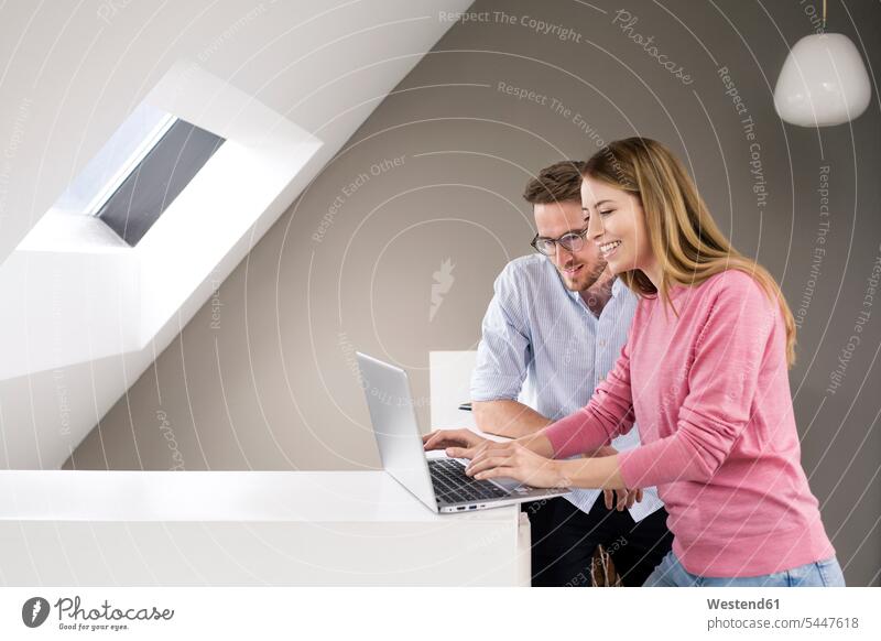 Lächelnder Mann und Frau teilen sich einen Laptop Notebook Laptops Notebooks Kollegen Arbeitskollegen Paar Pärchen Paare Partnerschaft Männer männlich weiblich