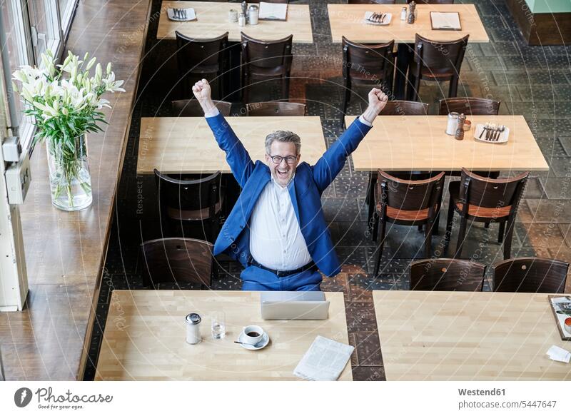 Jubelnder reifer Geschäftsmann im Café mit Laptop Cafe Kaffeehaus Bistro Cafes Cafés Kaffeehäuser Businessmann Businessmänner Geschäftsmänner glücklich Glück