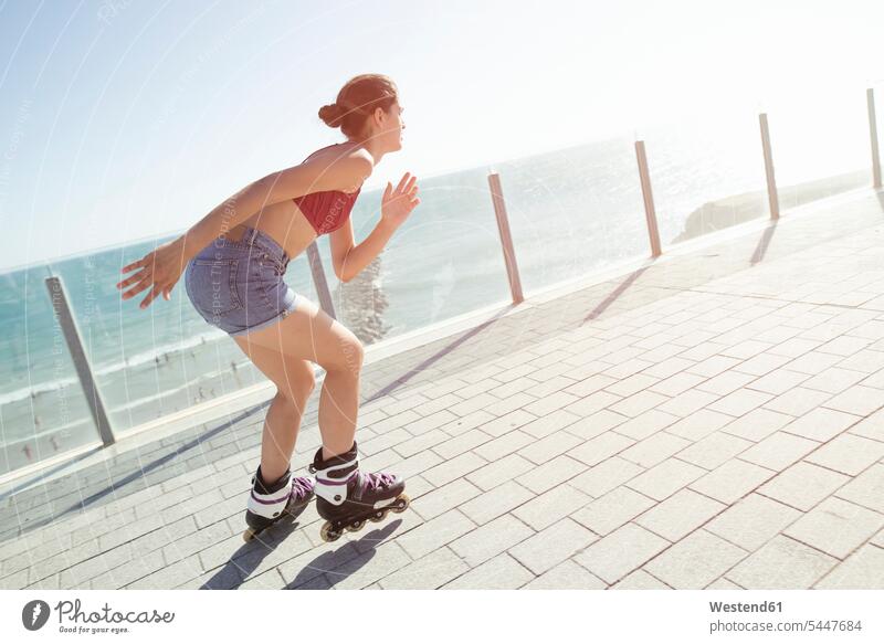 Junge Frau beim Inlineskaten auf der Strandpromenade an der Küste fahren Inlineskates Inline skates inline skate Inliner weiblich Frauen Rollerblades