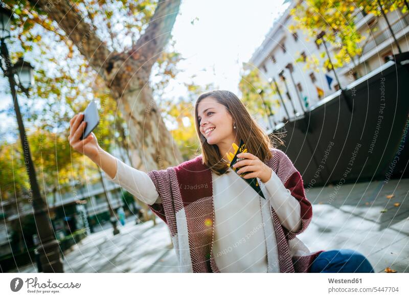 Junge Frau in Sevilla macht Selfie und isst Pommes frites Europäer Kaukasier Europäisch kaukasisch Oberkörper Oberkörperaufnahmen Halbfigur Take Away