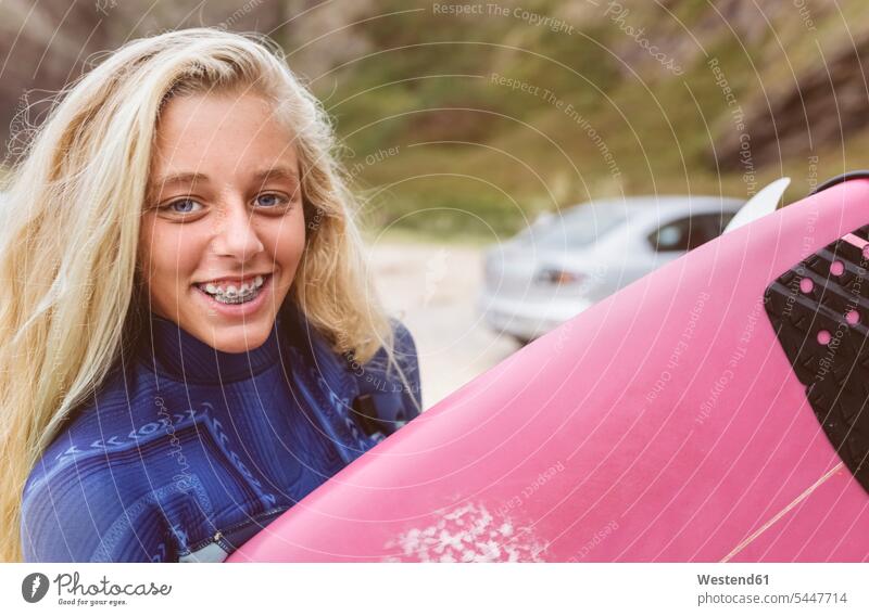 Spanien, Aviles, Porträt einer lächelnden jungen Surferin am Strand Surfbrett Surfbretter surfboard surfboards Portrait Porträts Portraits Beach Straende