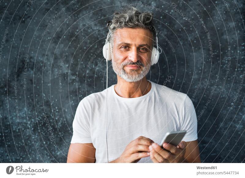 Porträt eines reifen Mannes, der ein Smartphone benutzt und Kopfhörer trägt Musik Anruf reifer Mann reife Männer telefonieren anrufen telephonieren hören hoeren