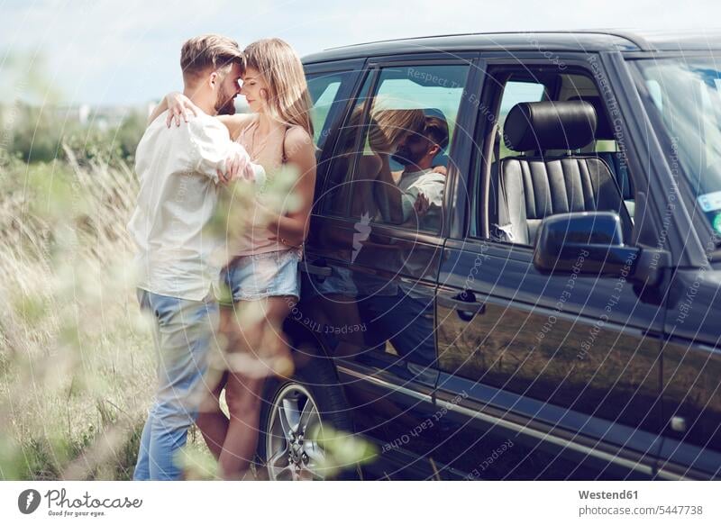 Zärtliches junges Paar vor dem Auto Wagen PKWs Automobil Autos Pärchen Paare Partnerschaft entspannt entspanntheit relaxt Liebe lieben Kraftfahrzeug