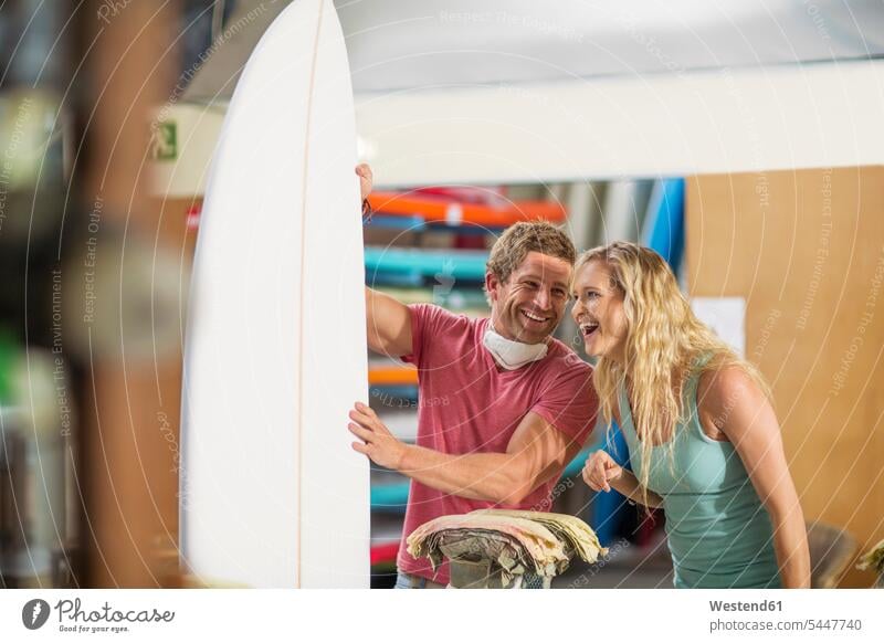 Surfboard-Shaper-Workshop, glücklicher Mann und Frau mit Surfbrett Werkstatt Werkstätte Werkstaette Werkstaetten Werkstätten lachen Surfbretter surfboard
