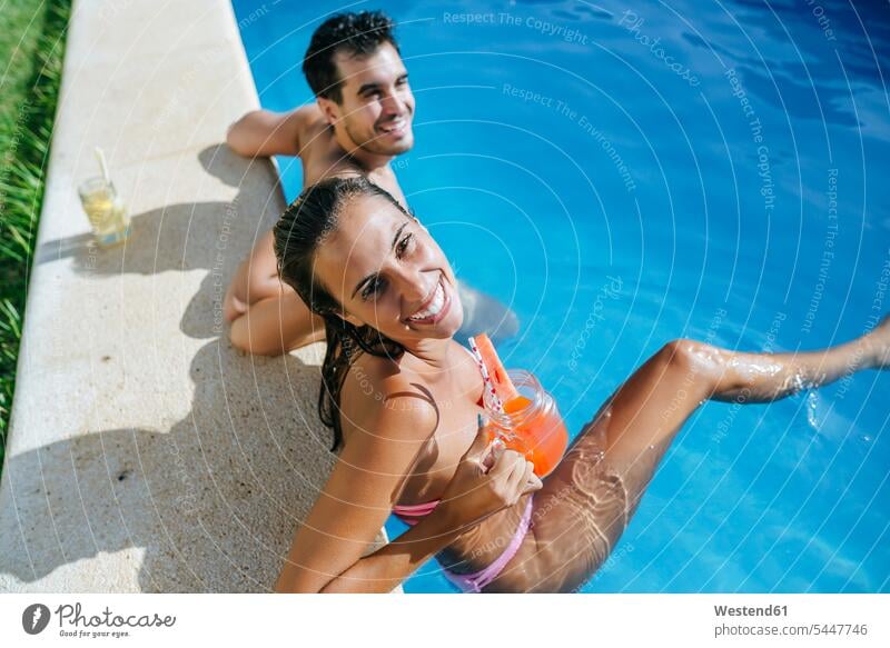 Glückliches Paar im Schwimmbad bei einem Drink am Pool Swimmingpool Swimmingpools Schwimmbecken Swimming Pool Swimming Pools lächeln glücklich glücklich sein