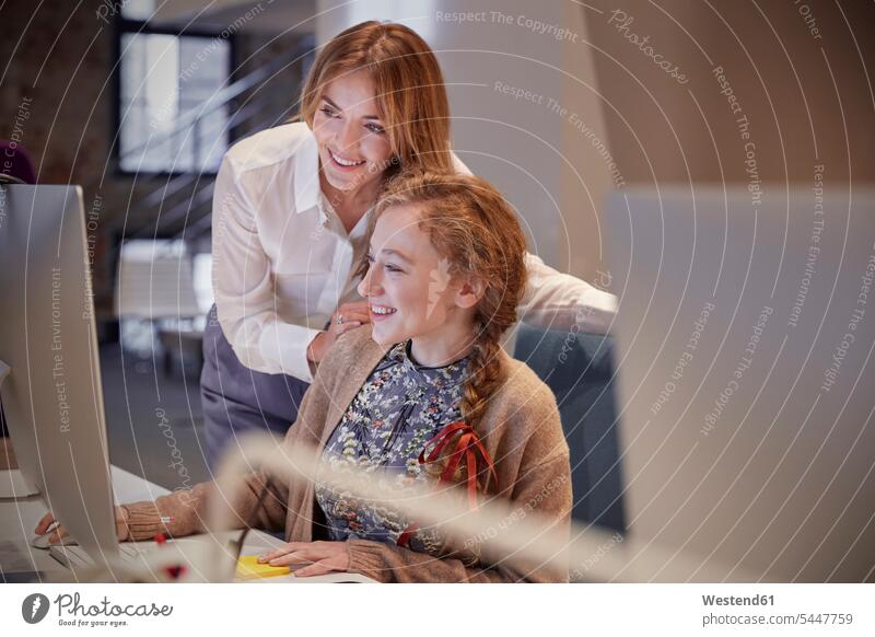 Kollegin hilft junger Frau bei der Arbeit PC Hilfe arbeiten Büro sitzen Schreibtisch Computer Arbeitsplatz Kollegen Tisch Freude lächeln lernen Chefin