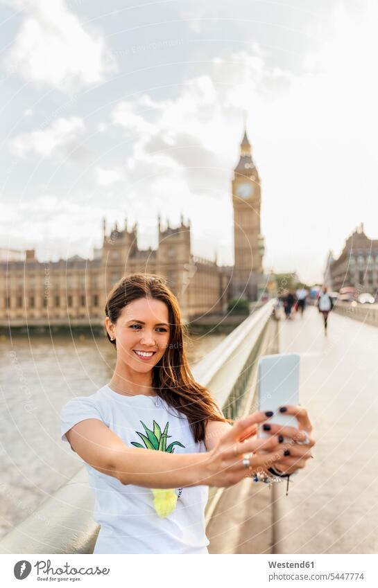 UK, London, schöne Frau macht ein Selfie auf der Westminster Bridge Selfies lächeln Handy Mobiltelefon Handies Handys Mobiltelefone weiblich Frauen Telefon