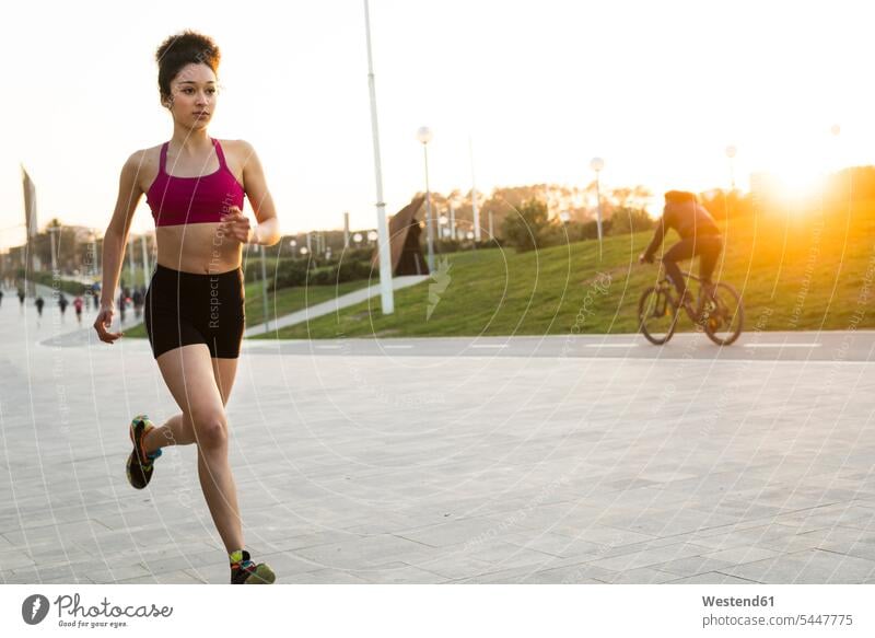 Junge Frau joggt in der Abenddämmerung Joggen Jogging weiblich Frauen Joggerin Joggerinnen Fitness fit Gesundheit gesund Sport Erwachsener erwachsen Mensch