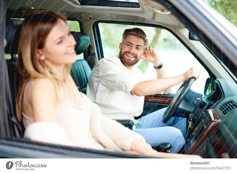Glückliches junges Paar im Auto Wagen PKWs Automobil Autos ansehen glücklich glücklich sein glücklichsein Pärchen Paare Partnerschaft lächeln Kraftfahrzeug