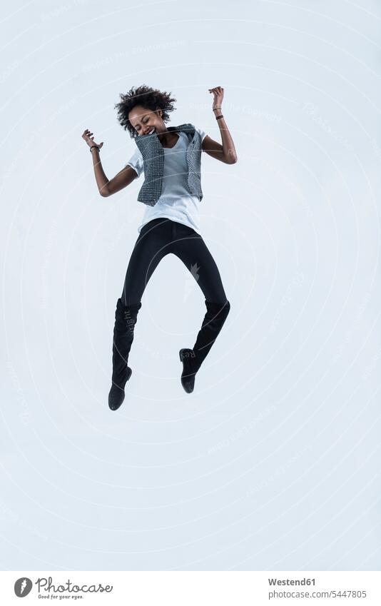 Frau springt vor grauem Hintergrund in die Luft weiblich Frauen Luftsprung Luftsprünge einen Luftsprung machen Luftspruenge springen hüpfen Erwachsener