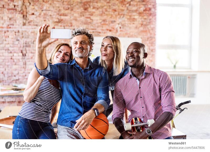 Glückliche Kollegen mit Basketball im Büro machen ein Selfie Selfies Office Büros fröhlich Fröhlichkeit Frohsinn Heiterkeit Arbeitskollegen Sport Arbeitsplatz