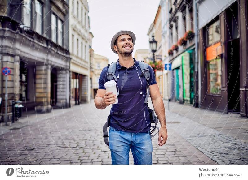 Reisender mit Rucksack, der mit Kaffee in der Hand durch die Stadt läuft Mann Männer männlich glücklich Glück glücklich sein glücklichsein lächeln Erwachsener