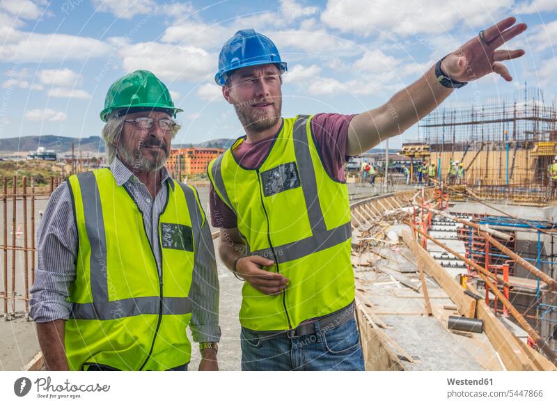 Bauarbeiter im Gespräch mit einem Mann auf einer Baustelle arbeiten Arbeit Baustellen sprechen reden Handwerker Handwerksberuf Handwerksberufe Gewerbe