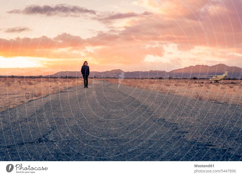 USA, Kalifornien, Joshua Tree, junger Mann geht bei Sonnenuntergang eine Straße entlang Der Weg nach vorne Wüste Wüsten Allein alleine einzeln unterwegs