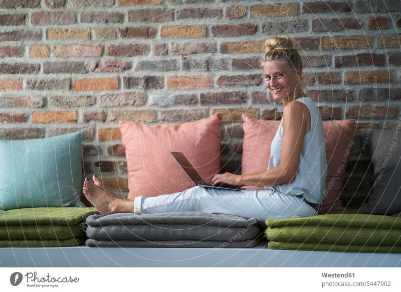 Reife Frau sitzt auf Couch, usine Laptop Notebook Laptops Notebooks weiblich Frauen arbeiten Arbeit Sofa Couches Liege Sofas sitzen sitzend Zuhause zu Hause