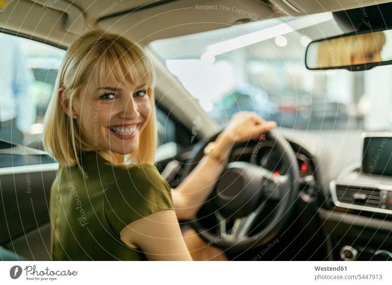 Blonde Frau wählt neues Auto im Autohaus Kundin Wagen PKWs Automobil Autos aussuchen auswählen Autohäuser Autohaeuser Autohandlung Autohandlungen kaufen Kauf