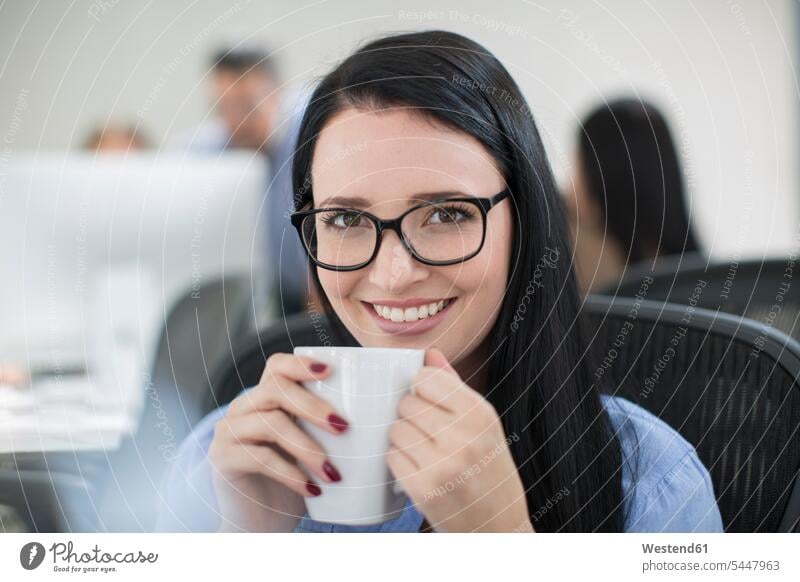 Mitarbeiterin genießt eine Tasse Kaffee an ihrem Schreibtisch Büro Office Büros Arbeitsplatz Arbeitsstätte Arbeitstelle lächeln Frau weiblich Frauen Getränk
