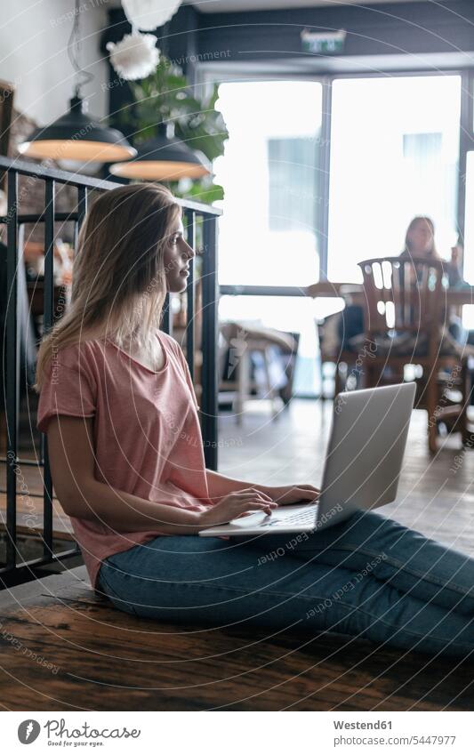 Junge Frau sitzt im Café und benutzt einen Laptop Notebook Laptops Notebooks sitzen sitzend Cafe Kaffeehaus Bistro Cafes Cafés Kaffeehäuser arbeiten Arbeit jung