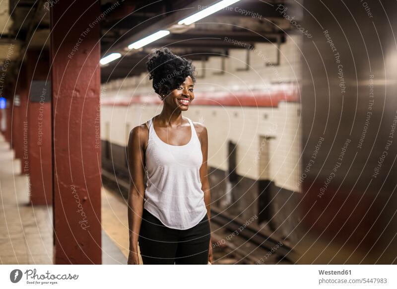 USA, New York City, Manhattan, lächelnde Frau wartet am Bahnsteig der U-Bahn-Station U-Bahnhofsbahnsteig U-Bahnhöfe U-Bahnhoefe U-Bahnhofsbahnsteige Bahnsteige