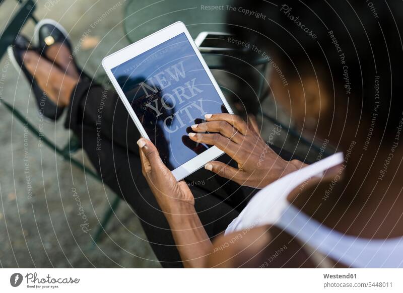USA, New York City, Frau sitzt in einem Park mit Reiseführer auf Tablett weiblich Frauen Tablet Computer Tablet-PC Tablet PC iPad Tablet-Computer Erwachsener