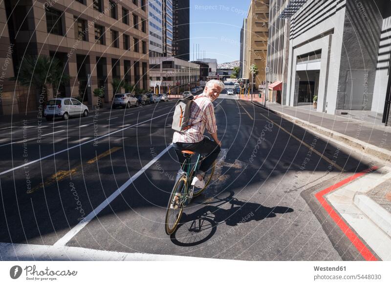 Älterer Mann fährt Fahrrad in der Stadt Bikes Fahrräder Räder Rad radfahren fahrradfahren radeln unterwegs auf Achse in Bewegung lächeln staedtisch städtisch