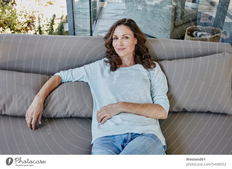 Frau sitzt entspannt auf der Couch auf der Terrasse weiblich Frauen entspanntheit relaxt sitzen sitzend glücklich Glück glücklich sein glücklichsein Terrassen