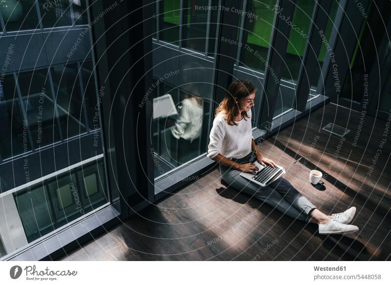 Geschäftsfrau sitzt am Boden in einem leeren Büro und benutzt einen Laptop sitzen sitzend Geschäftsfrauen Businesswomen Businessfrauen Businesswoman