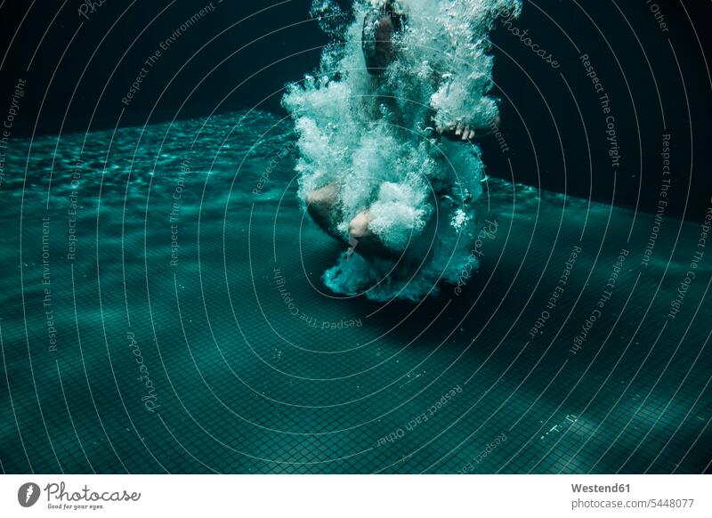 Luftblasen umgeben den Mann, der in ein Schwimmbecken springt springen hüpfen Unterwasser unter Wasser Unterwasseraufnahme Unterwasserfoto Blase Bläschen Blasen