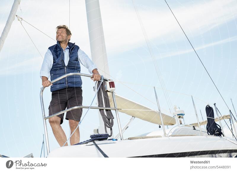 Porträt eines lächelnden reifen Mannes auf seinem Segelboot, der in die Ferne schaut Männer männlich Segeln segelnd segelt Erwachsener erwachsen Mensch Menschen