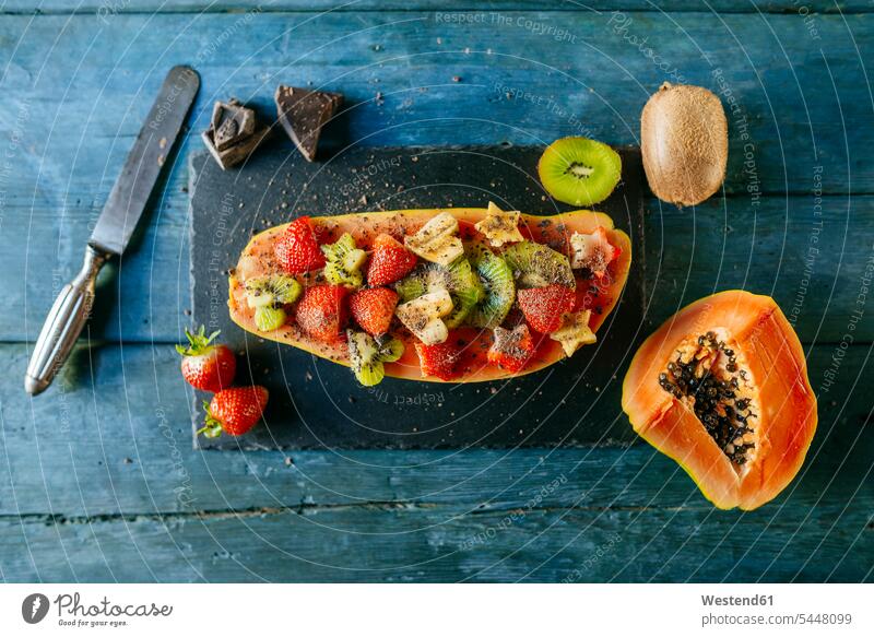 Halbe Papaya dekoriert mit Bananen-, Kiwi- und Erdbeerstückchen auf einem Schieferteller Vitamine geschnitten abgeschnitten Gesunde Ernährung Ernaehrung