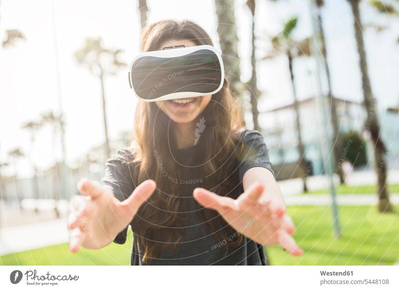 Junge Frau mit VR-Brille im Freien lachen Virtuelle Realität Virtuelle Realitaet weiblich Frauen positiv Emotion Gefühl Empfindung Emotionen Gefühle fühlen
