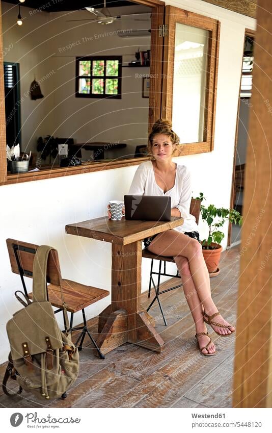 Porträt einer jungen Frau mit Laptop und Kaffeetasse auf der Veranda eines Cafés sitzend Notebook Laptops Notebooks Computer Rechner Cafe Kaffeehaus Bistro
