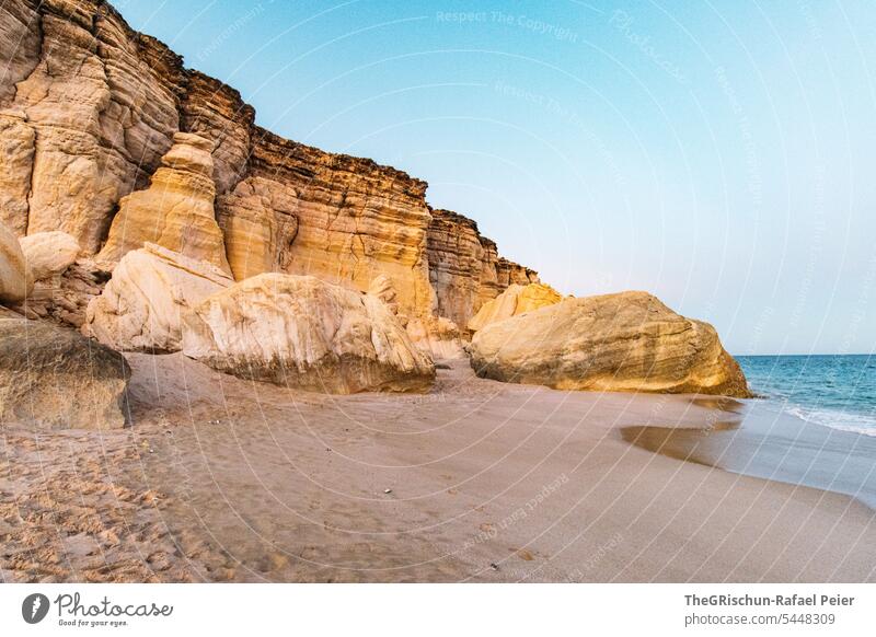 Felsen und Sand am Meer in Abendstimmung Stimmung Strand Steine Wasser Küste Oman Himmel Wolken Landschaft Horizont Natur blau Sommer Tourismus Bucht Urlaub
