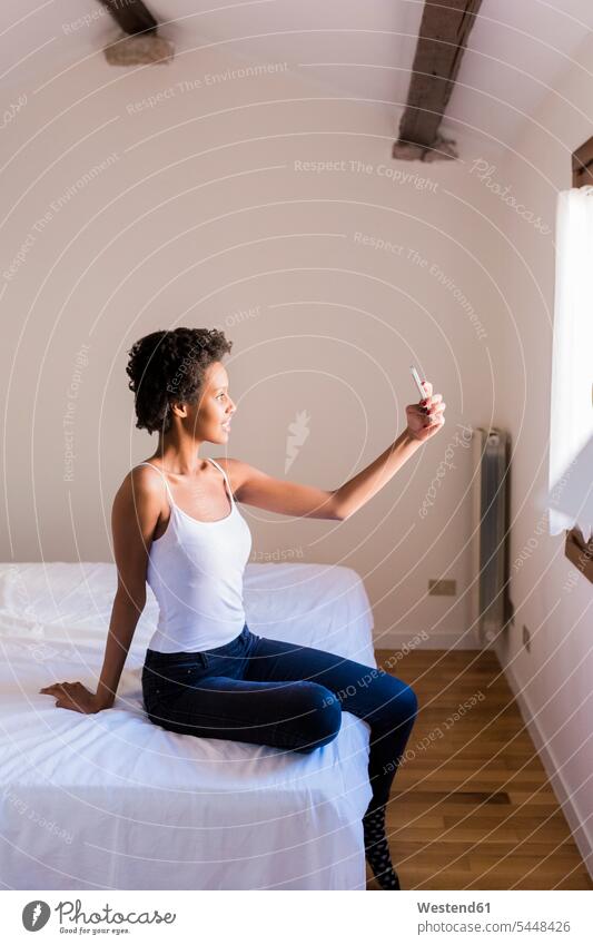 Junge Frau macht ein Selfie im Schlafzimmer Bett Betten weiblich Frauen Zuhause zu Hause daheim Selfies Handy Mobiltelefon Handies Handys Mobiltelefone