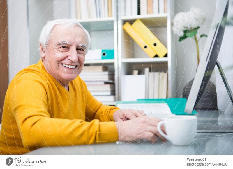 Älterer Mann arbeitet am Computer mit einer Tasse Kaffee sitzen arbeiten trinken Senior Getränk Food and Drink Erwachsener Mensch Senioren Freude glücklich