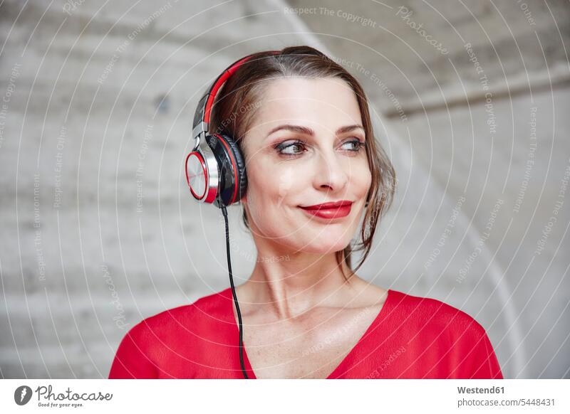 Lächelnde Frau, die mit Kopfhörern Musik hört Kopfhoerer weiblich Frauen hören hoeren lächeln Erwachsener erwachsen Mensch Menschen Leute People Personen Freude