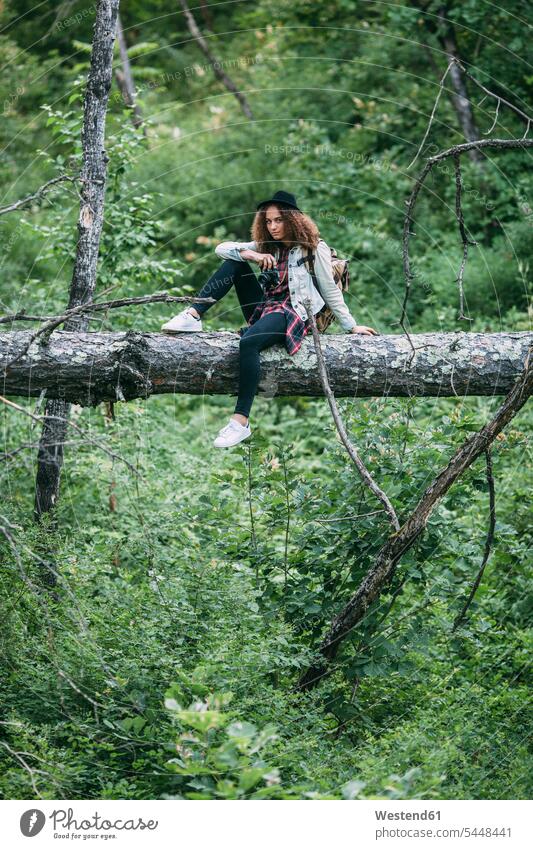 Teenager-Mädchen mit Kamera auf Totholz in der Natur sitzend Teenagerin junges Mädchen Teenagerinnen weiblich junge Frau Wald Forst Wälder Jugendliche