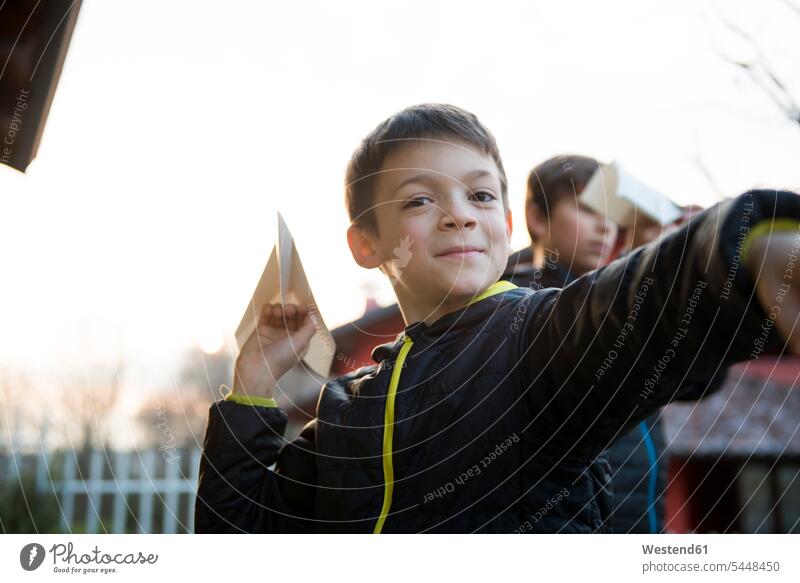 Porträt eines lächelnden Jungen mit Papierflugzeug Buben Knabe Knaben männlich Portrait Porträts Portraits Papierflieger Kind Kinder Kids Mensch Menschen Leute