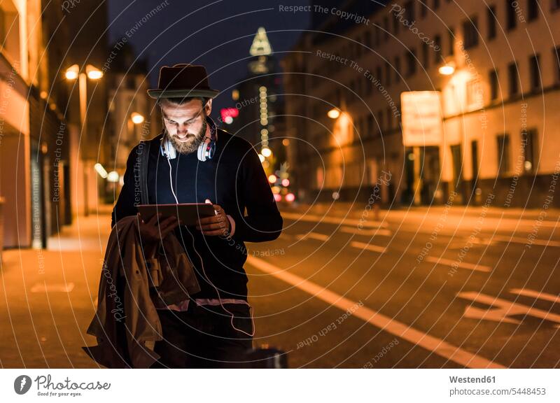 Stilvoller junger Mann mit Tablette auf nächtlicher Stadtstraße Tablet Computer Tablet-PC Tablet PC iPad Tablet-Computer Männer männlich Nacht nachts Rechner